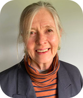 A portrait headshot og Dr Gillian Claridge. She has her hair tied up and wears a grey jacket and an orange and grey turtleneck top. She smiles warmly.